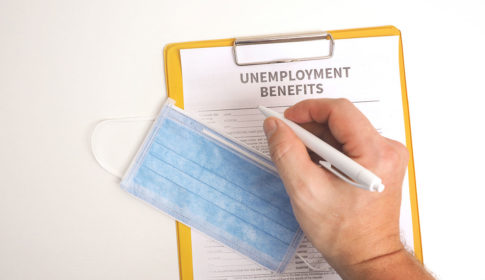 hand filling out unemployment benefits form and mask