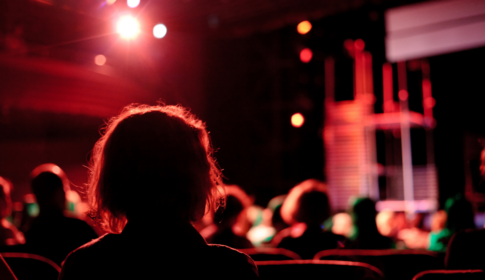 woman sits in the audience during the performance of a play