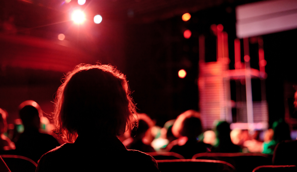 woman sits in the audience during the performance of a play