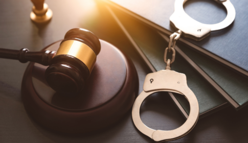 judge's gavel with handcuffs sitting on top of a desk