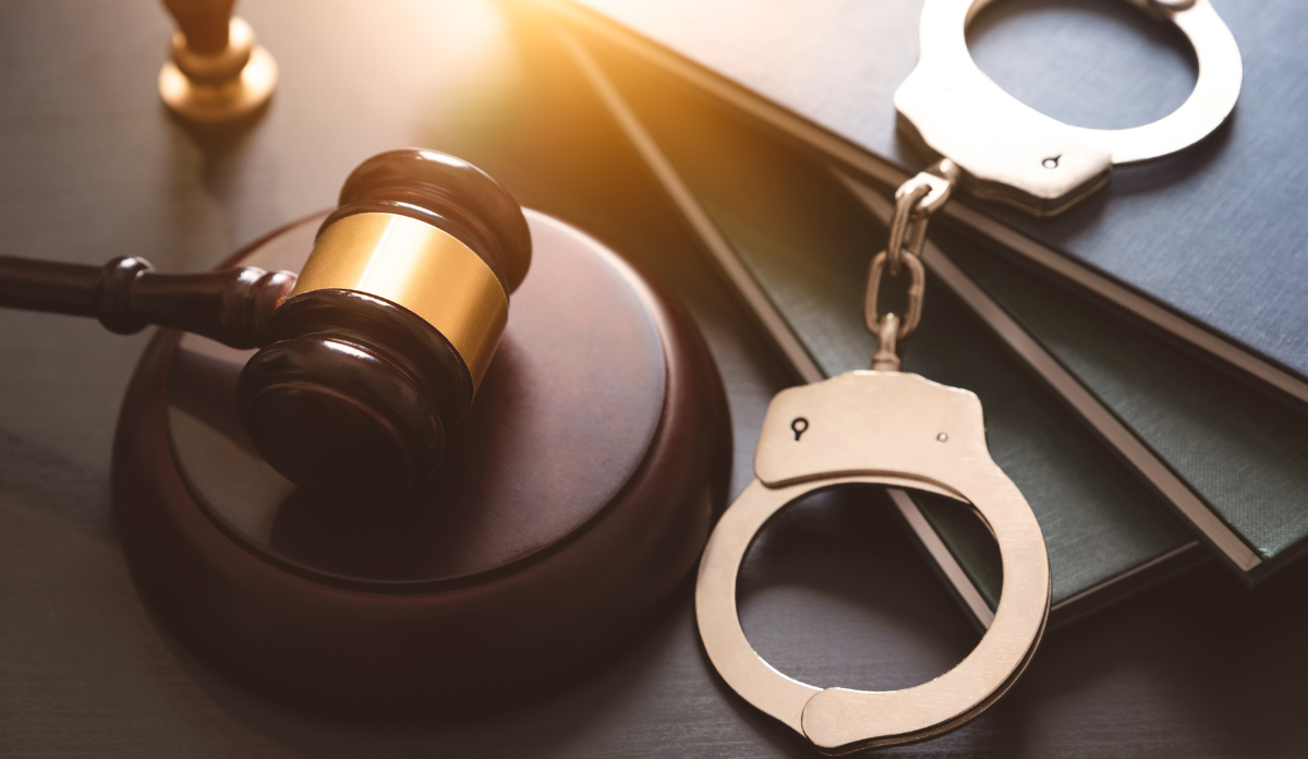 judge's gavel with handcuffs sitting on top of a desk