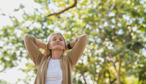 Elderly woman relaxing and breathing fresh air with sunlight in outdoors park