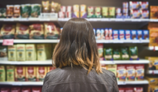 back of woman's head looking at groceries on the store shelves
