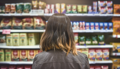 back of woman's head looking at groceries on the store shelves