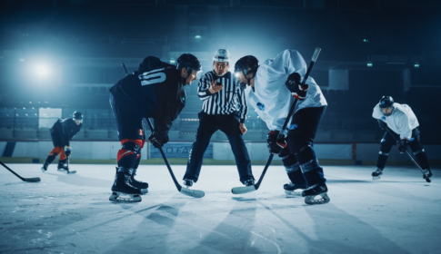 two hockey players face off before puck is dropped by referee