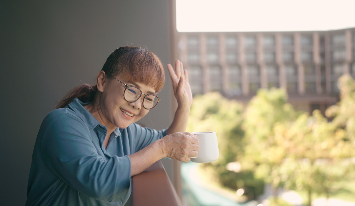 older asian woman smiling and waving to her neighbor below