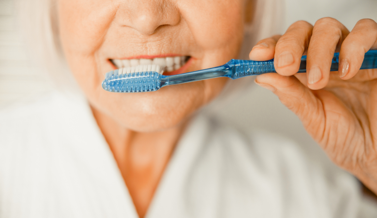 close up of older woman brushing teeth, signifying good oral health