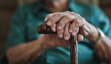 close up of elderly man's hands, leaning on cane