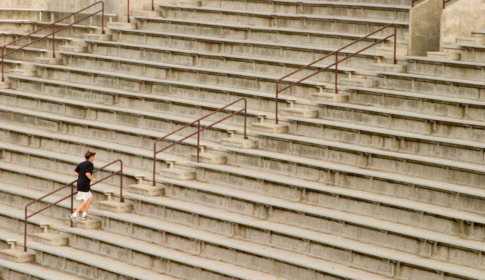 man taking care of his health by walking up stairs at a stadium