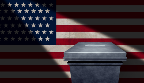 American flag in background with a light shining on a ballot box –US elections and voting concept