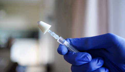 Hand holding a syringe with a mucosal atomization decive (MAD) used for intranasal application of drugs, like naloxone, a drug used for opioid overdose prevention